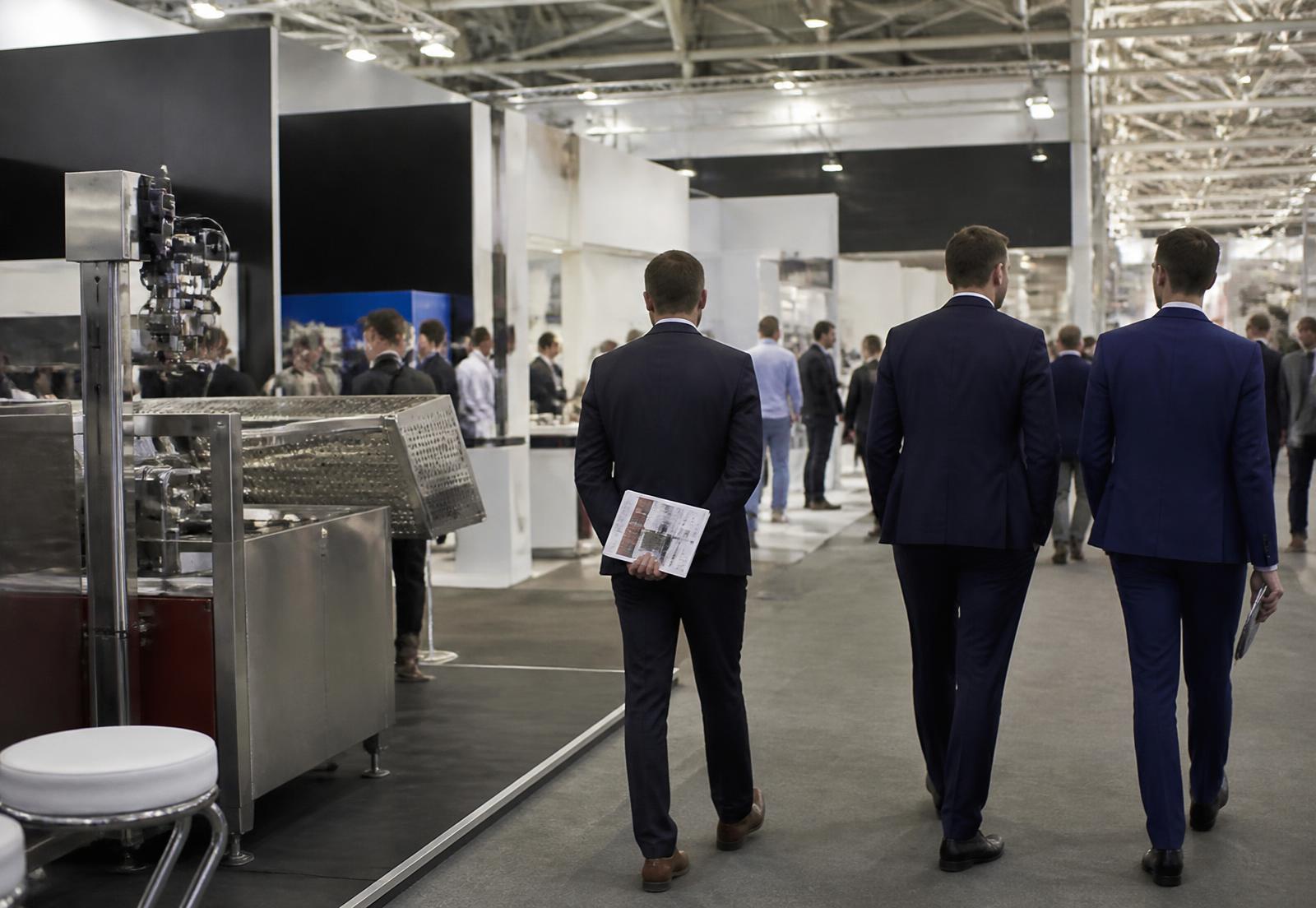 Padiglione fieristico industriale con stand e visitatori professionali